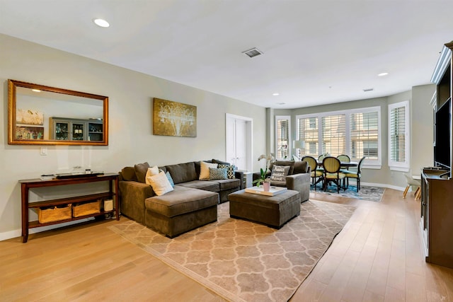 living area with visible vents, light wood finished floors, and baseboards