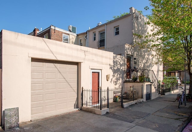 304 5th St, Jersey City, NJ 07302 - view of front facade with fence, a garage, concrete driveway, and stucco siding