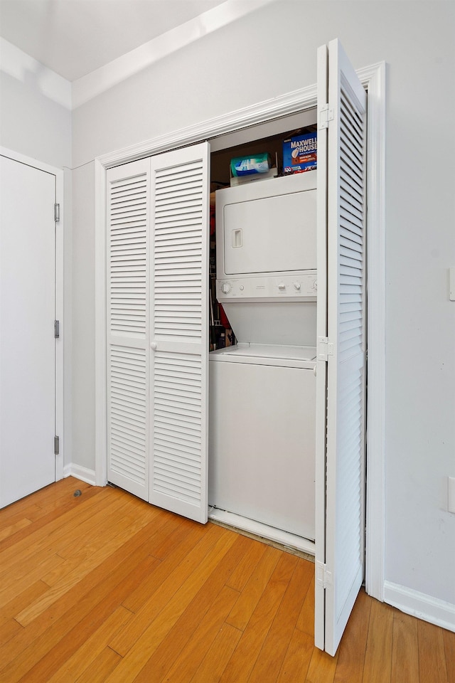 laundry area featuring wood-type flooring and stacked washer / drying machine