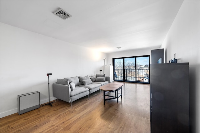 living room featuring visible vents, baseboards, and wood finished floors