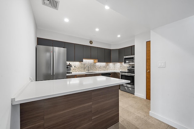 kitchen featuring visible vents, backsplash, a peninsula, stainless steel appliances, and a sink