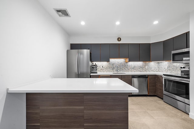 kitchen with visible vents, a peninsula, a sink, stainless steel appliances, and light countertops