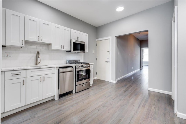 402 Grand St Unit 3S, Hoboken, NJ 07030 - kitchen with appliances with stainless steel finishes, backsplash, light wood-style floors, and white cabinets