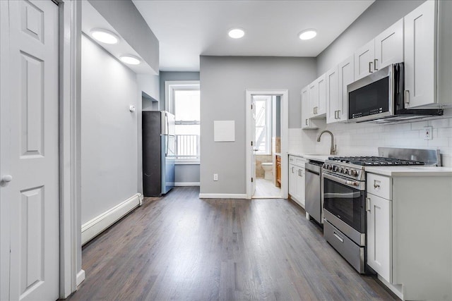 402 Grand St Unit 3S, Hoboken, NJ 07030 - kitchen with appliances with stainless steel finishes, baseboard heating, decorative backsplash, light countertops, and dark wood-style floors