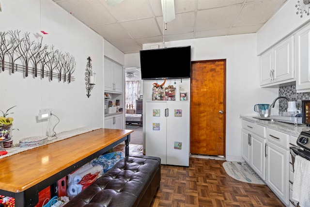 kitchen featuring white cabinetry, light stone counters, tasteful backsplash, dark parquet flooring, and range