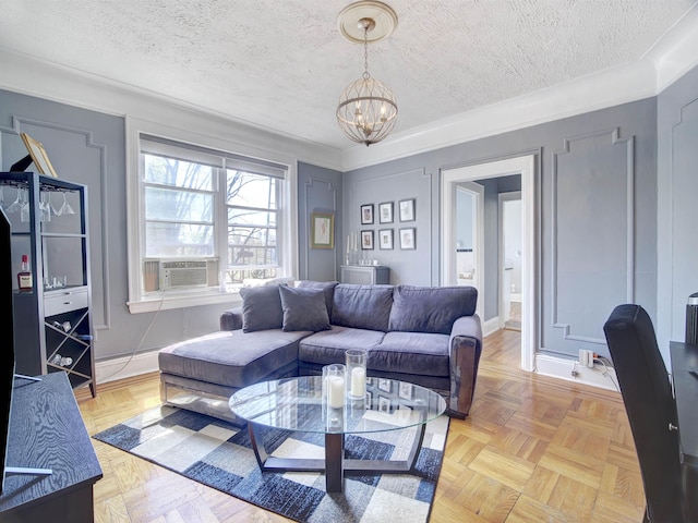 living area with a chandelier, baseboards, cooling unit, and a textured ceiling