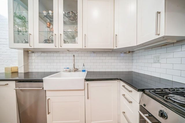kitchen with dark countertops, range, white cabinetry, tasteful backsplash, and stainless steel dishwasher