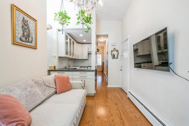living area with light wood-style floors, a notable chandelier, baseboards, and a baseboard radiator