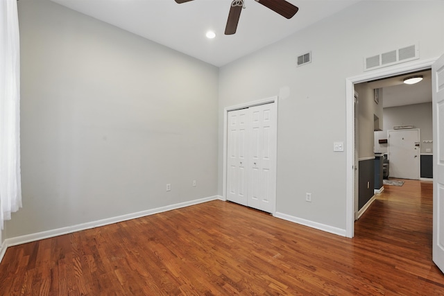 unfurnished bedroom with baseboards, a closet, wood finished floors, and visible vents