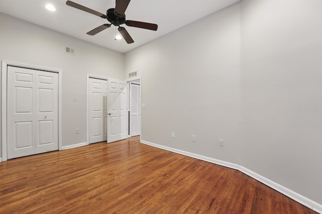 unfurnished bedroom with multiple closets, baseboards, and wood finished floors