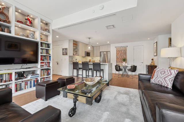 living room with light wood finished floors, visible vents, and recessed lighting