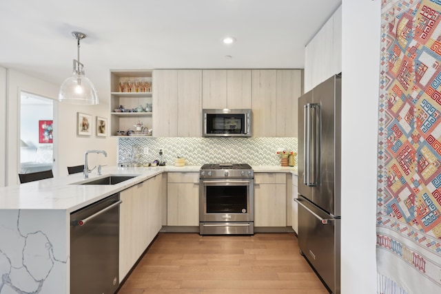 kitchen featuring a sink, premium appliances, modern cabinets, and a peninsula