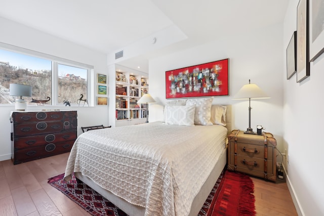 bedroom with visible vents, wood finished floors, and baseboards