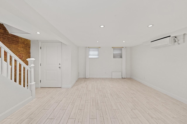 basement featuring light hardwood / wood-style floors and a wall mounted air conditioner