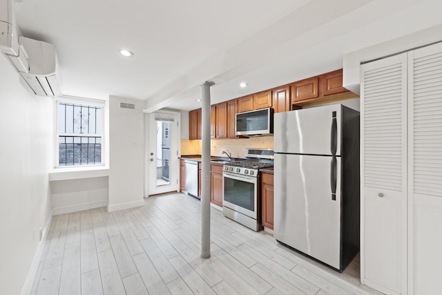 kitchen with light wood-type flooring, decorative backsplash, stainless steel appliances, and a wall mounted air conditioner