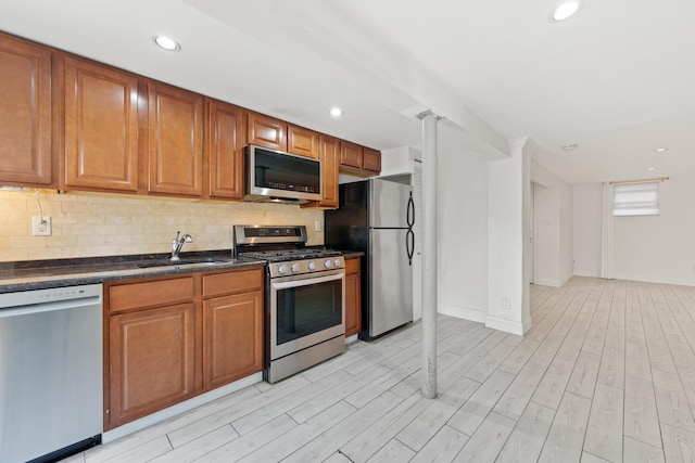 kitchen with backsplash, sink, stainless steel appliances, and light hardwood / wood-style floors