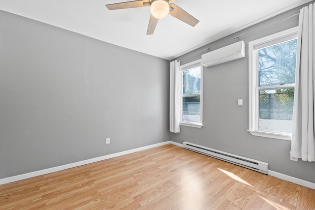 spare room featuring light wood-type flooring, a wealth of natural light, an AC wall unit, and a baseboard radiator