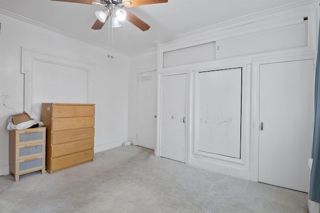 unfurnished bedroom featuring ceiling fan, crown molding, light carpet, and multiple closets