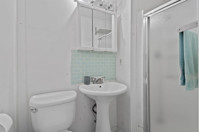 bathroom featuring toilet, an enclosed shower, sink, and tasteful backsplash