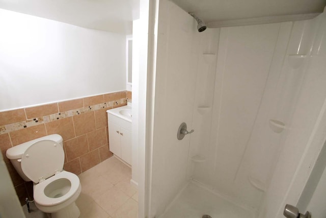 bathroom featuring a wainscoted wall, tile patterned flooring, a shower stall, tile walls, and toilet