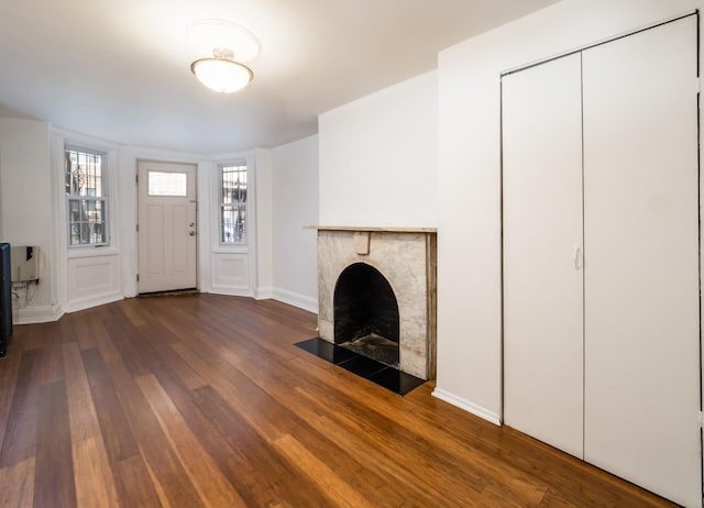 unfurnished living room featuring baseboards, a fireplace with flush hearth, and hardwood / wood-style floors