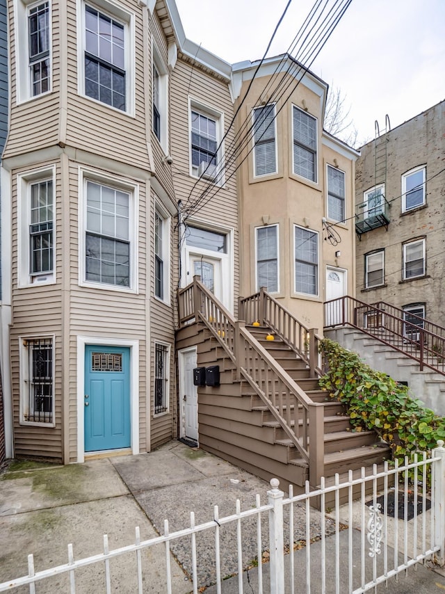 townhome / multi-family property featuring a fenced front yard and stairs