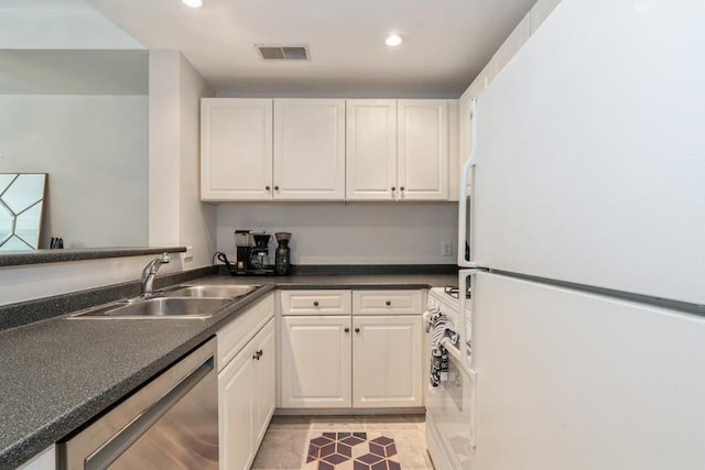 kitchen with stainless steel dishwasher, freestanding refrigerator, white cabinets, a sink, and visible vents