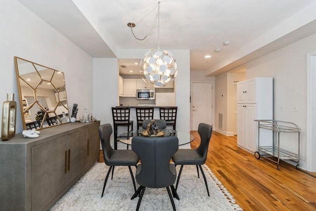 dining space with recessed lighting, light wood finished floors, baseboards, visible vents, and a notable chandelier