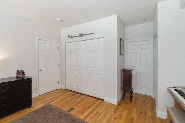 bedroom with light wood-style floors, a closet, and baseboards