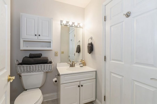 bathroom featuring toilet, vanity, and baseboards