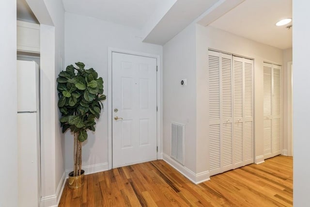 entrance foyer featuring visible vents, wood finished floors, and baseboards