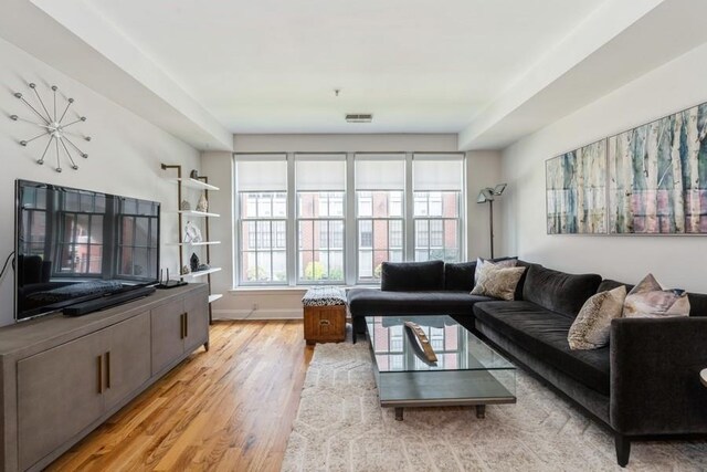 living room with visible vents, light wood-type flooring, and baseboards