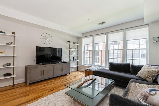 living room featuring wood finished floors, visible vents, and baseboards