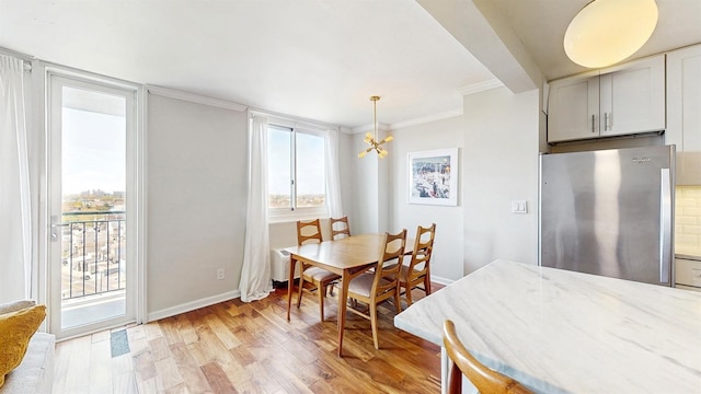 dining room with a chandelier, ornamental molding, a healthy amount of sunlight, and light wood-style flooring