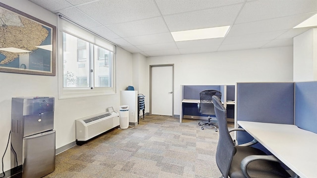 carpeted office featuring baseboards, a wall mounted AC, and a drop ceiling