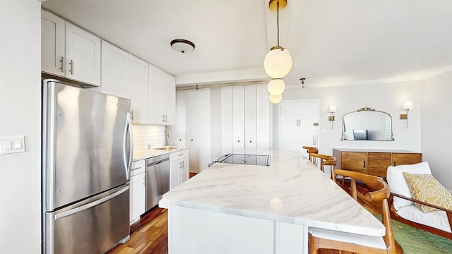 kitchen with a center island, white cabinets, tasteful backsplash, light stone counters, and stainless steel appliances