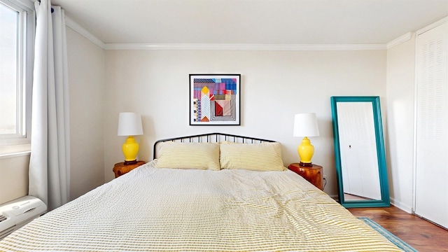 bedroom with crown molding, baseboards, and wood finished floors