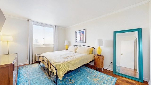 bedroom featuring crown molding, baseboards, and wood finished floors