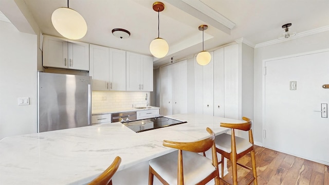 kitchen featuring a breakfast bar, a sink, light wood-style floors, stainless steel appliances, and decorative backsplash