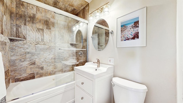bathroom with bath / shower combo with glass door, vanity, and toilet