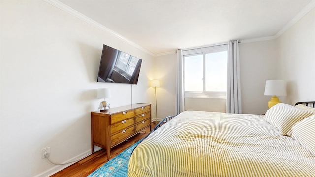 bedroom with baseboards, ornamental molding, and wood finished floors
