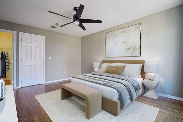 bedroom featuring ceiling fan, dark hardwood / wood-style flooring, a walk in closet, and a closet