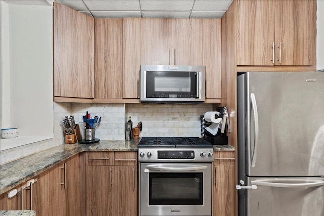 186 Wayne St Unit 118D, Jersey City, NJ 07302 - kitchen featuring stainless steel appliances, decorative backsplash, stone countertops, and brown cabinets