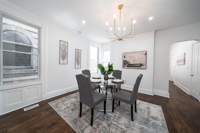 dining room featuring an inviting chandelier, baseboards, wood finished floors, and visible vents