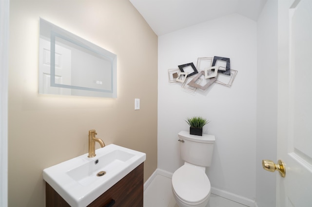 bathroom featuring vanity, baseboards, vaulted ceiling, and toilet