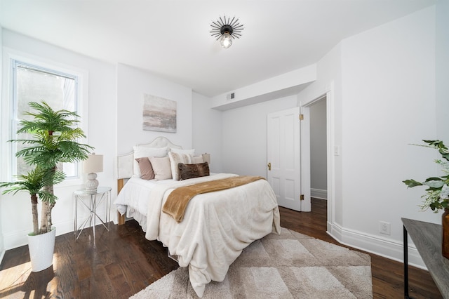 bedroom featuring baseboards, visible vents, and wood finished floors