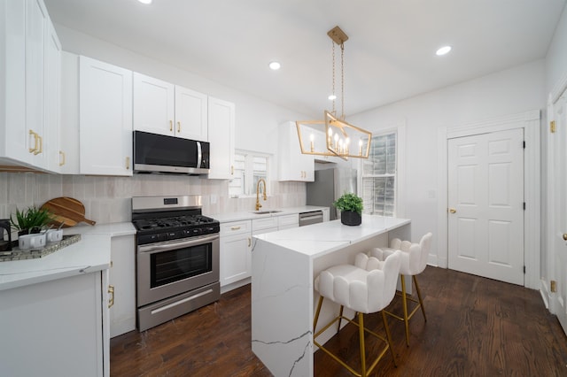 kitchen with backsplash, white cabinetry, appliances with stainless steel finishes, and a sink