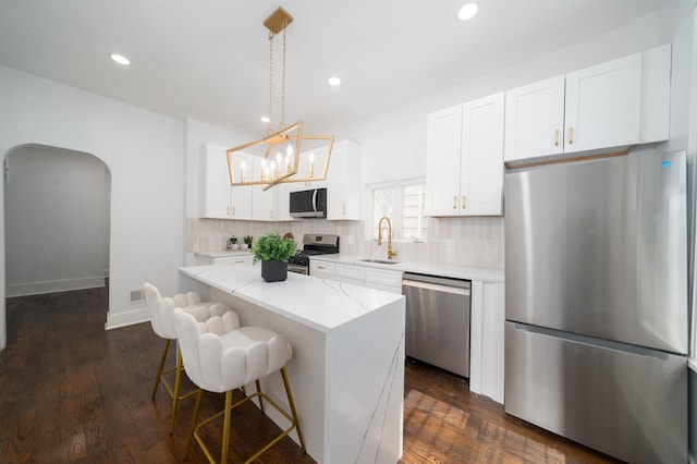 kitchen featuring a kitchen island, a kitchen bar, tasteful backsplash, a sink, and stainless steel appliances