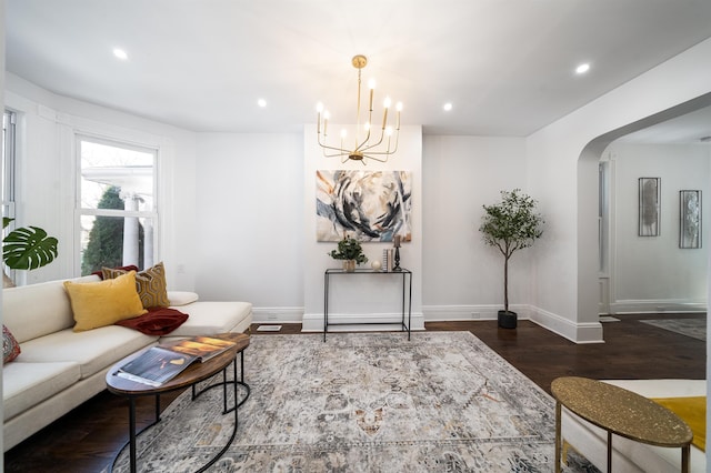 living room featuring arched walkways, wood finished floors, baseboards, a notable chandelier, and recessed lighting