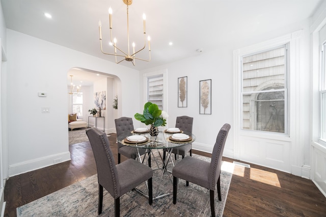 dining room with an inviting chandelier, built in features, wood finished floors, baseboards, and arched walkways